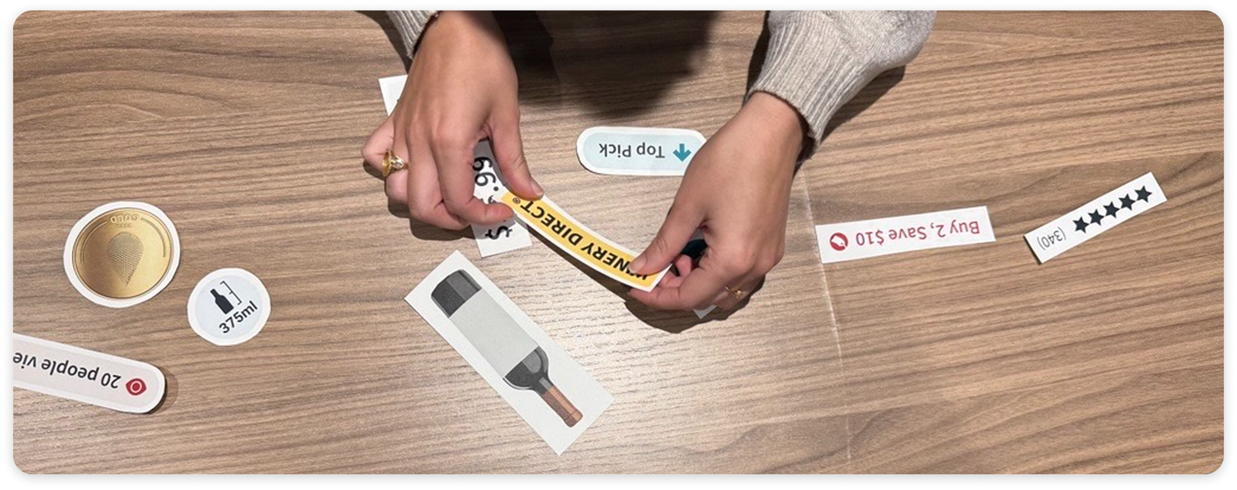 Hands arranging printed cutouts of tile elements during in-store card-sorting research